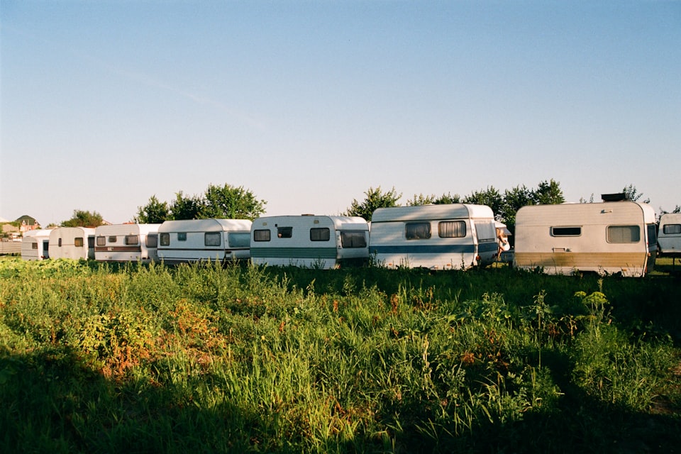A row of caravans parked tightly together in a field at a busy UK touring site