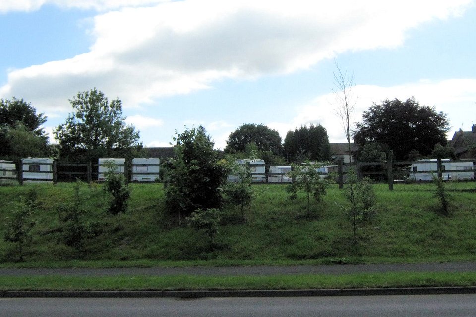 Rows of touring caravans parked behind a fence in a UK caravan storage field