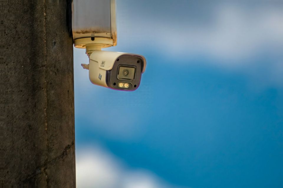 A security camera mounted on a pole against a blue sky at a UK campsite
