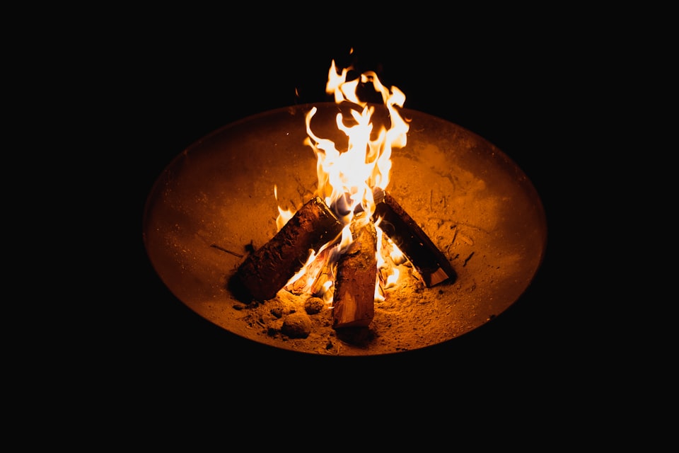 A crackling fire in a raised metal fire pit at a UK campsite in the evening
