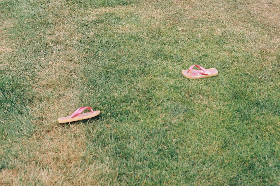 A pair of flip flops left behind on a grass campsite pitch