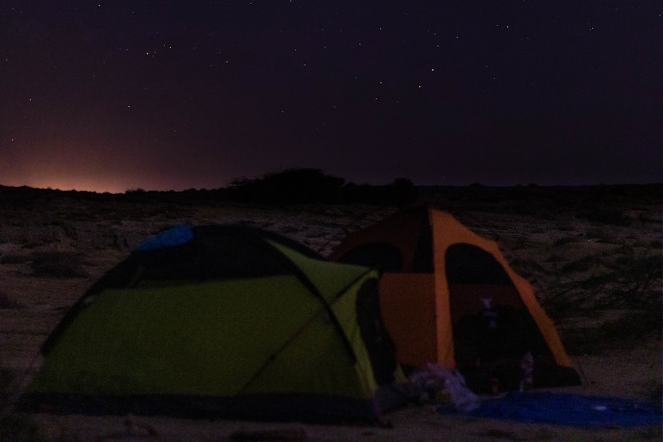 Tents pitched under a dark, star-filled night sky at a UK campsite