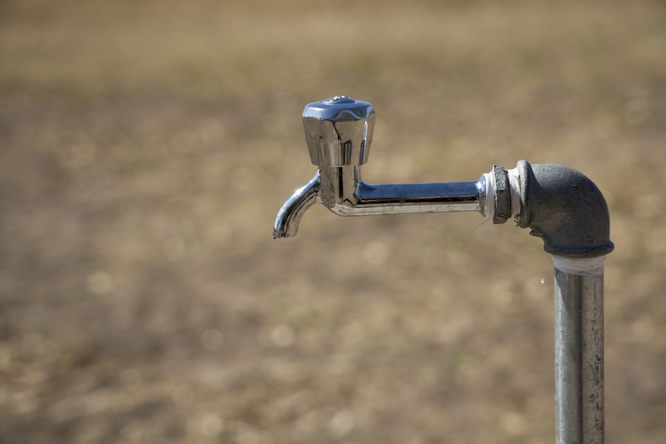 Close-up of an outdoor standpipe tap in a field, the kind of rarely used outlet campsites need to check for legionella risk