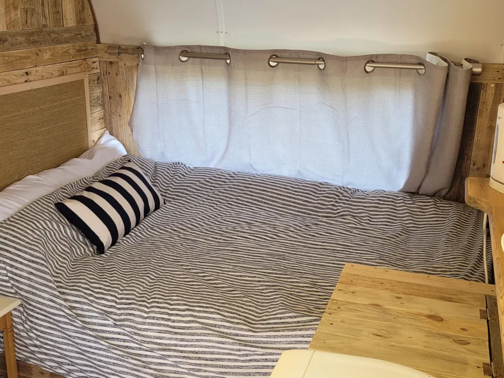 Inside Nancy, the restored 1970s caravan, with a made-up double bed and wood panelling