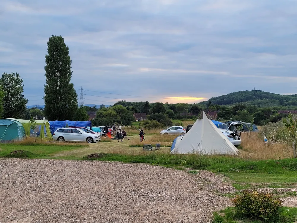 Tents and a bell tent pitched in the Orchard at Bredon-Vale, with Bredon Hill behind