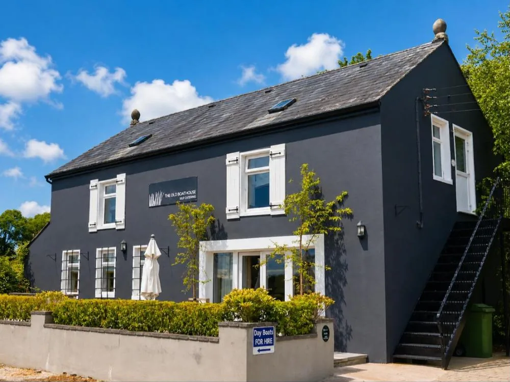 The Old Boathouse, a dark grey two-storey house with white shutters and an outside stair