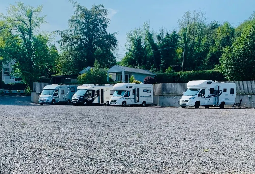 Four motorhomes parked on the gravel hardstanding at Knockninny, with trees and a lodge behind