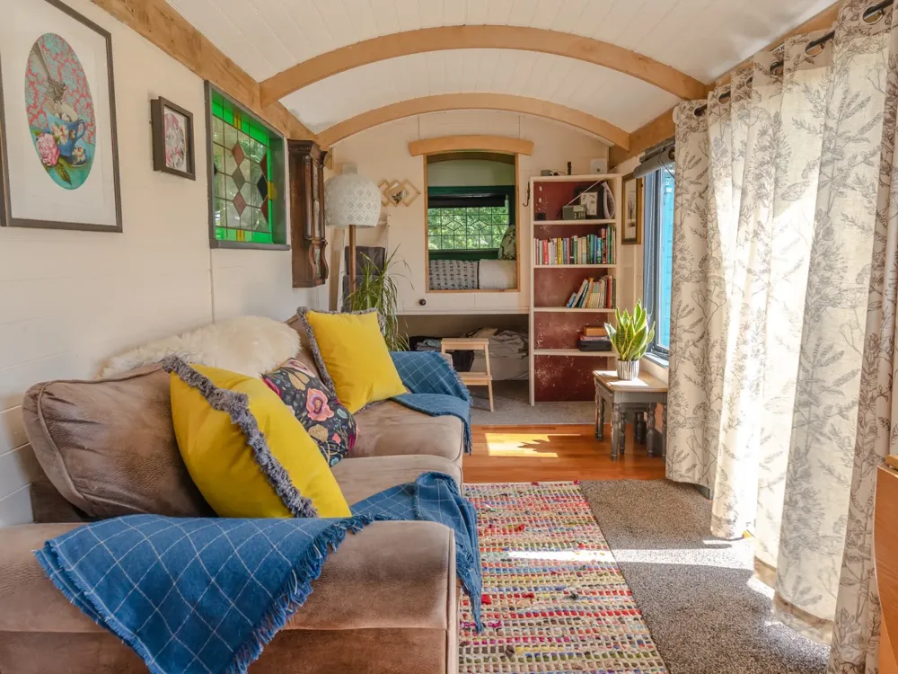 Inside the Tinkers Hut, with a sofa under the curved white ceiling and a bed at the far end