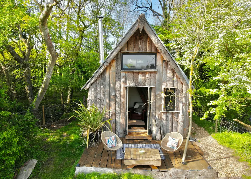 The Tiny House in daylight, with its deck and chairs