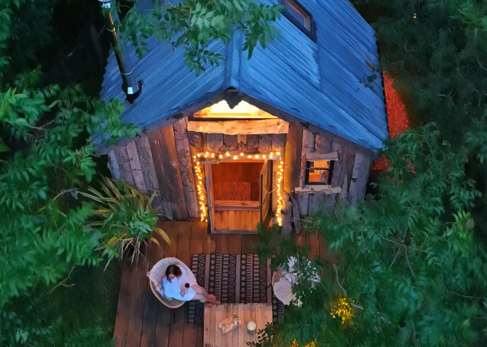 The Tiny House at Wardley Hill lit up at dusk among the trees